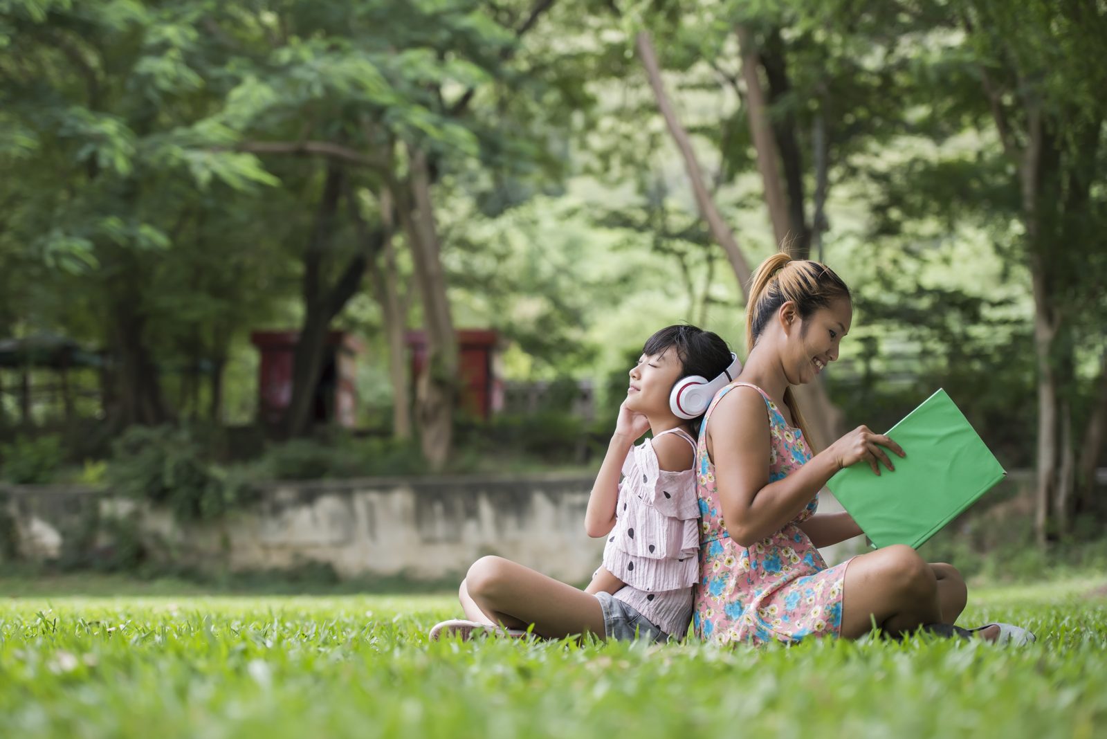 A mother and daughter reading a story together in a park